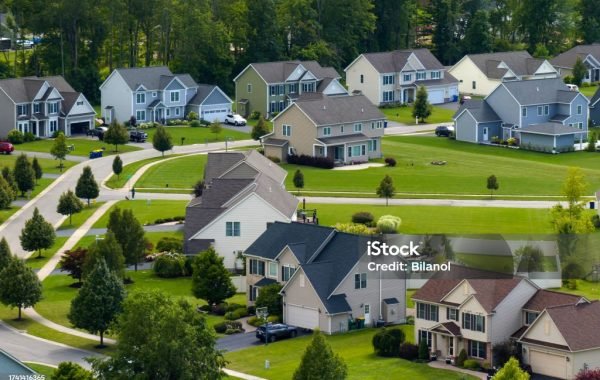 Low-density two story private homes in rural residential suburbs outside of Rochester, New York. Upscale suburban houses with large lot size and green grassy lawns in summer season.